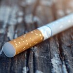 cigarette tenue par une main réfléchissant aux risques